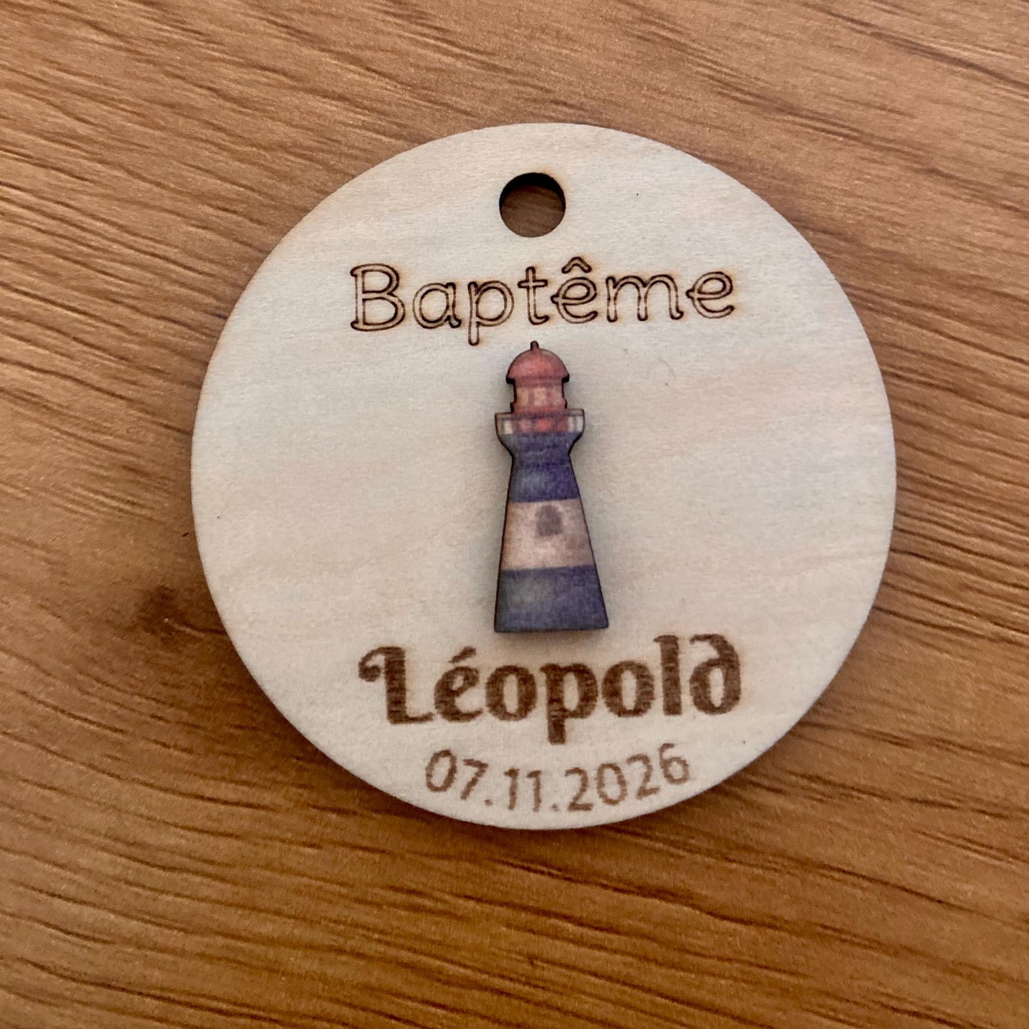Étiquette bois 'Phare bleu' accrochée à un contenant en verre pour un baptême."