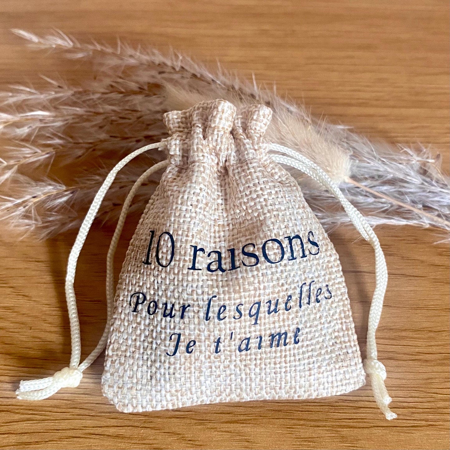 Un mini pochon en tissu entrouvert laissant apparaître des petits cœurs en bois gravés.