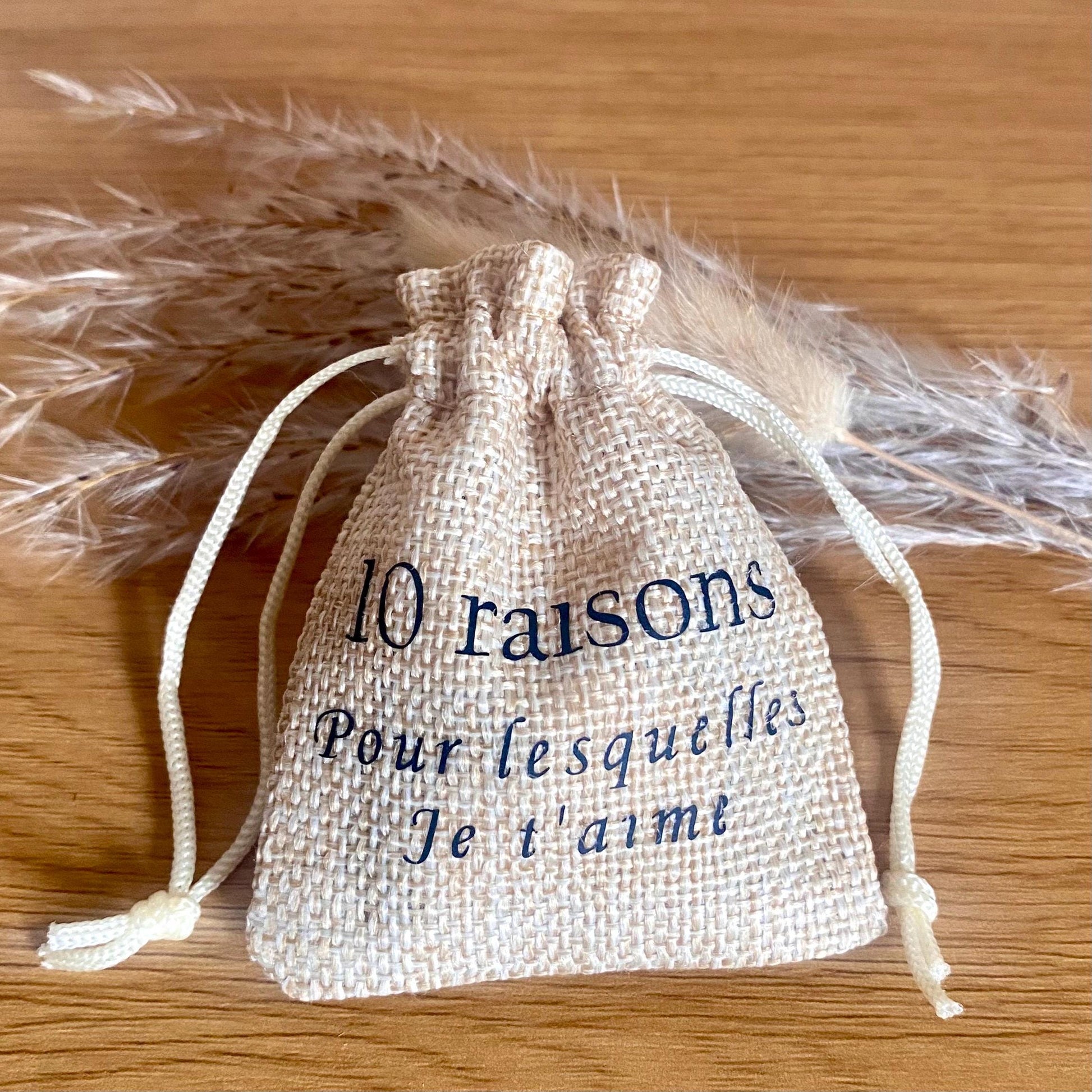 Un mini pochon en tissu entrouvert laissant apparaître des petits cœurs en bois gravés.
