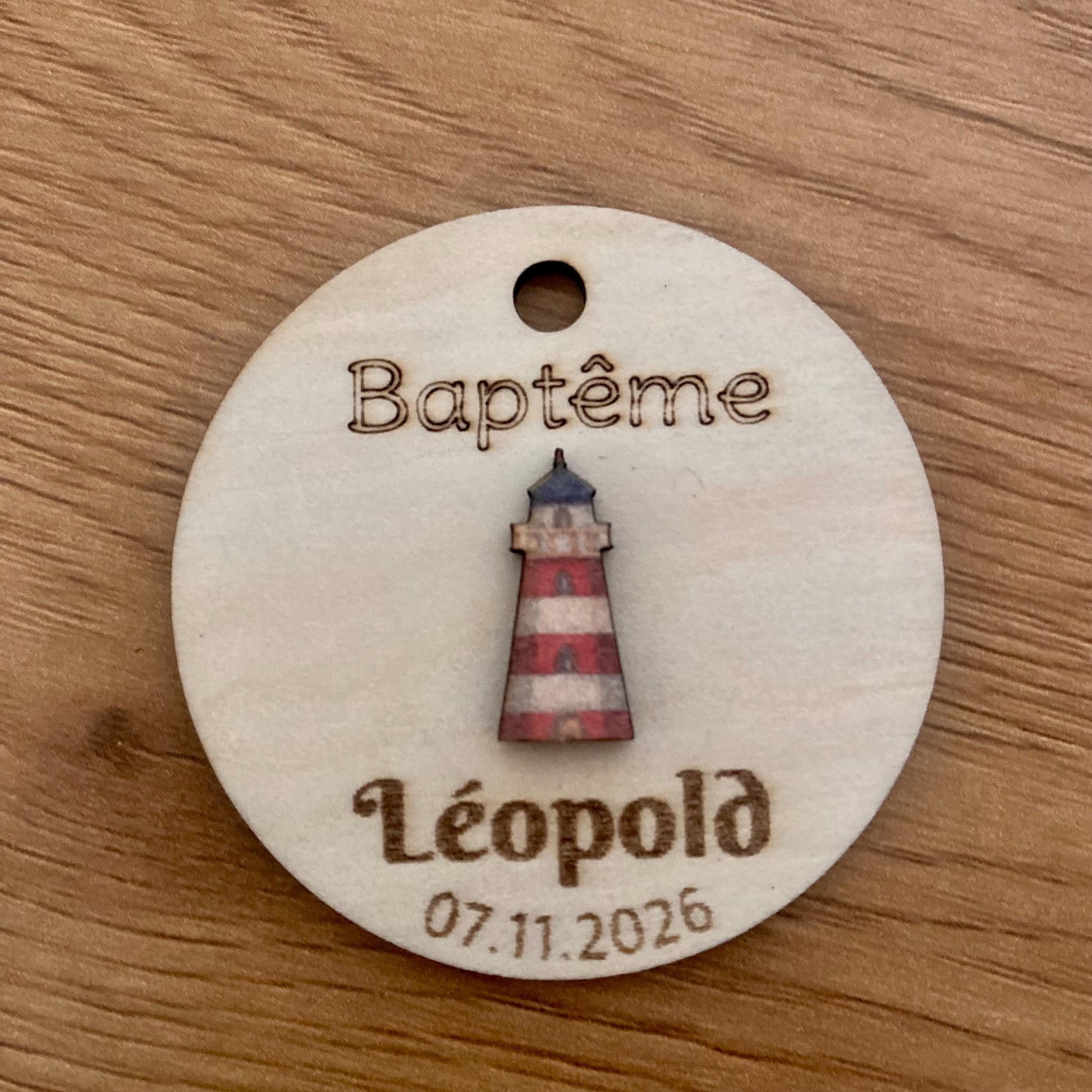 Étiquette bois 'Phare rouge' accrochée à un contenant en verre pour un baptême."