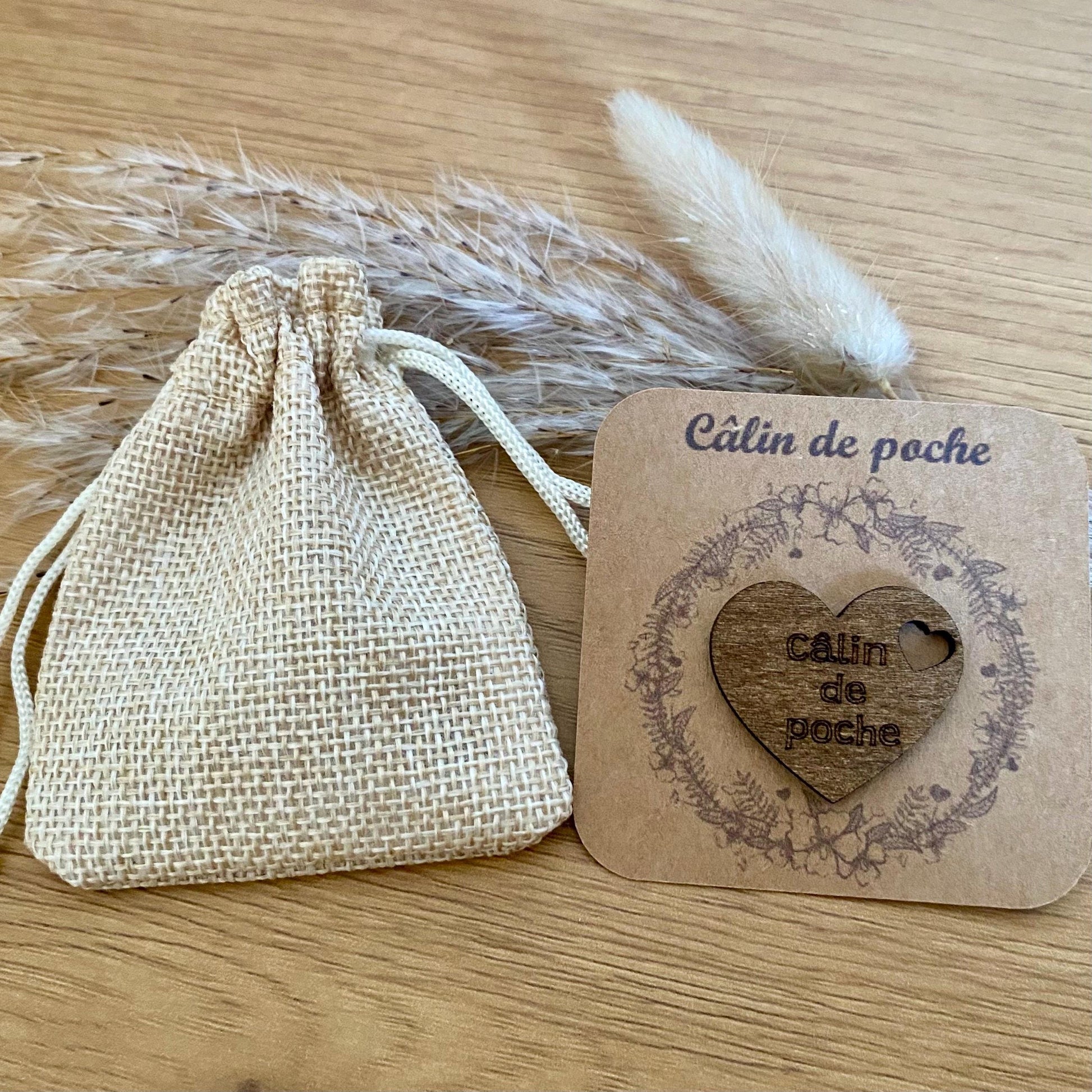 Câlin de poche coeur en bois gravé sur son support kraft et accompagné de son petit pochon