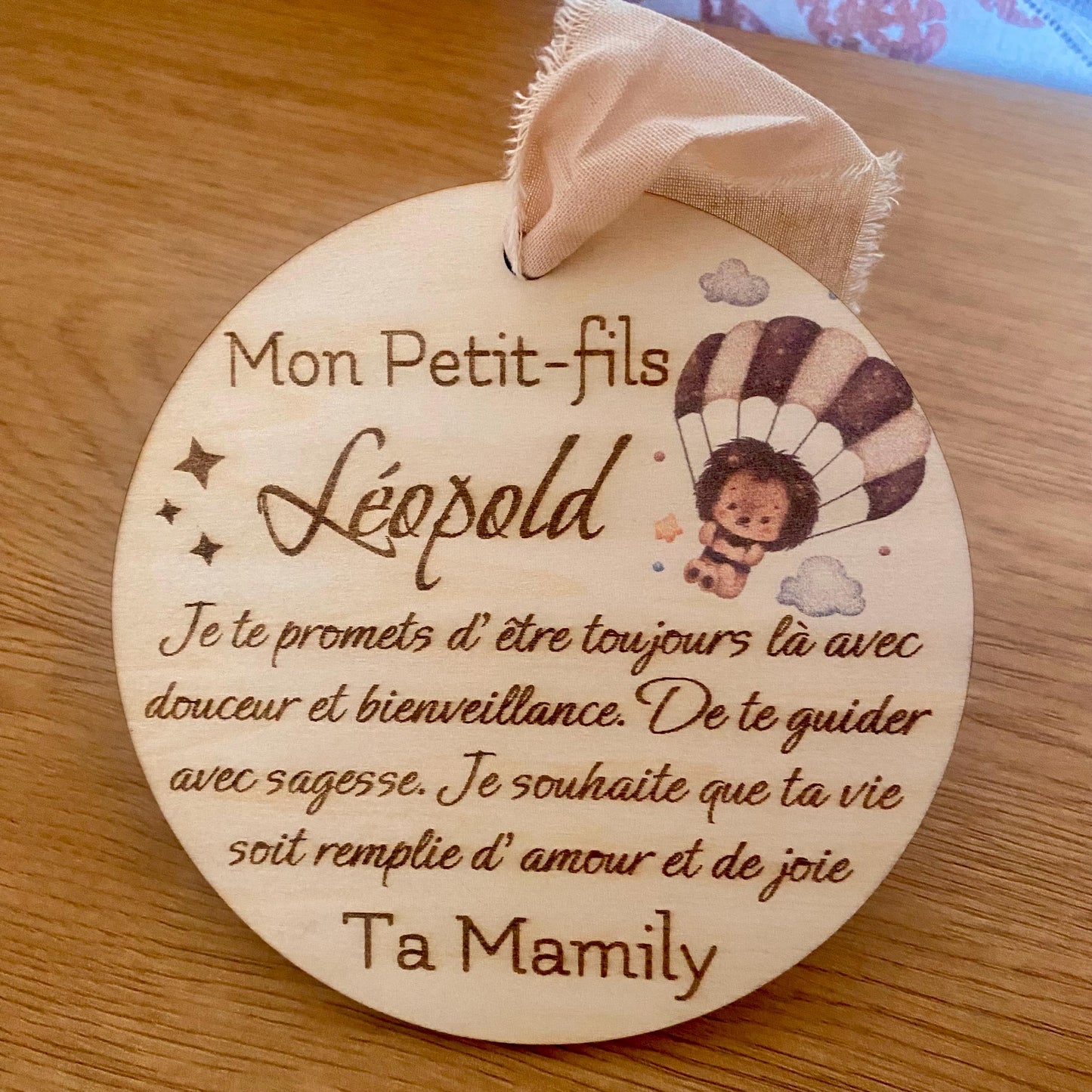carte ronde en bois avec texte gravé avec motif hérisson, suspendue par son ruban en mousseline beige sur un fond clair.