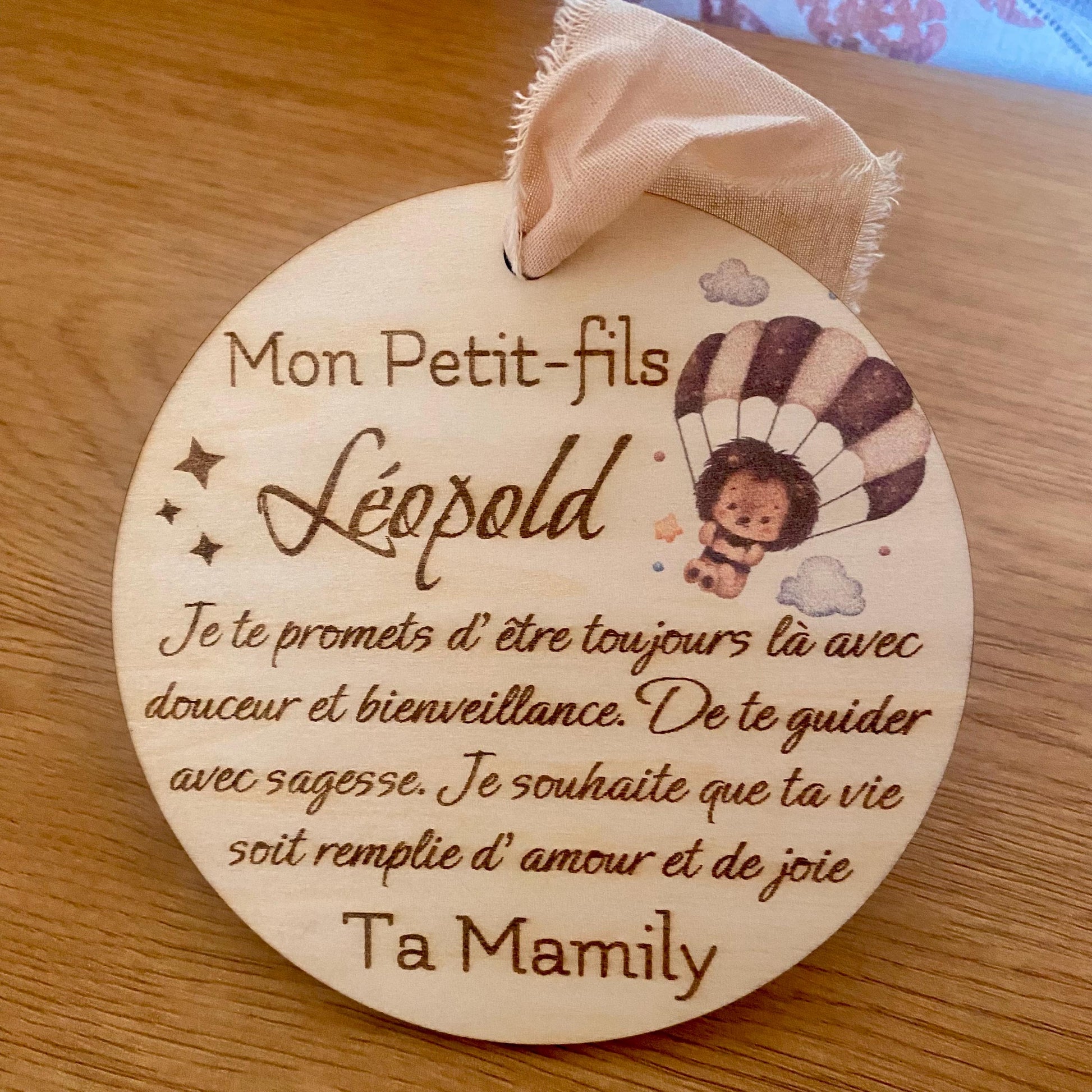 carte ronde en bois avec texte gravé avec motif hérisson, suspendue par son ruban en mousseline beige sur un fond clair.