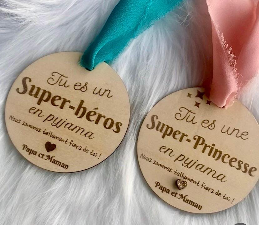 La suspension bois "Super-Héros" mise en valeur par un ruban coloré, avec une lumière douce et bienveillante.