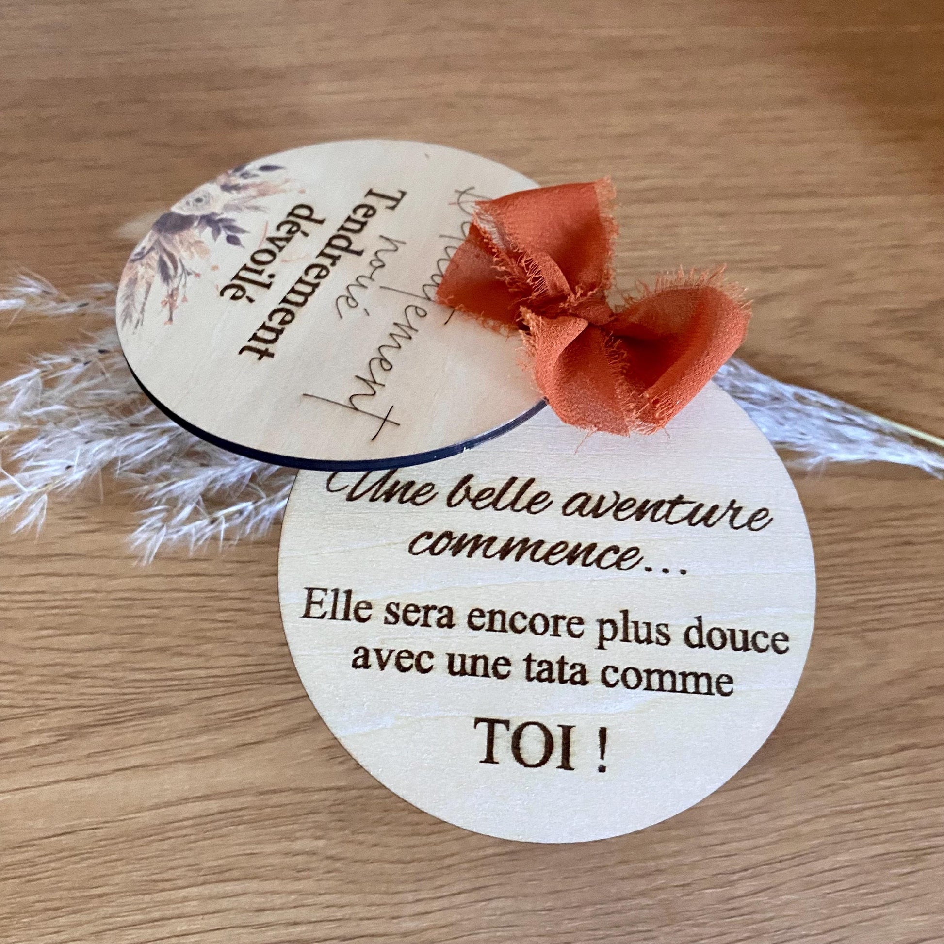 Coffret annonce grossesse composé de deux cartes en bois gravées, maintenues par un ruban mousseline terracotta chic, posé sur un support naturel.