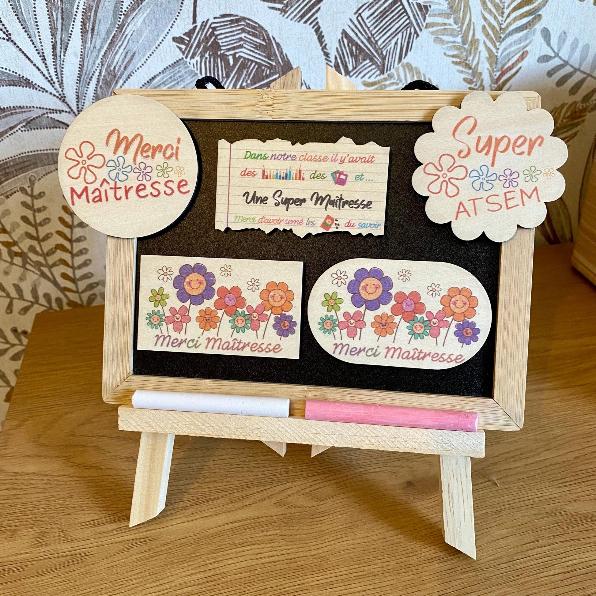 Magnets en bois personnalisés en forme de fleur et de feuille de cahier, disposés à côté de leur emballage cadeau en papier de soie beige."