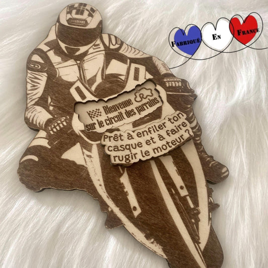 Le motard sur sa moto en bois, posé sur un support, montrant son design élégant.
