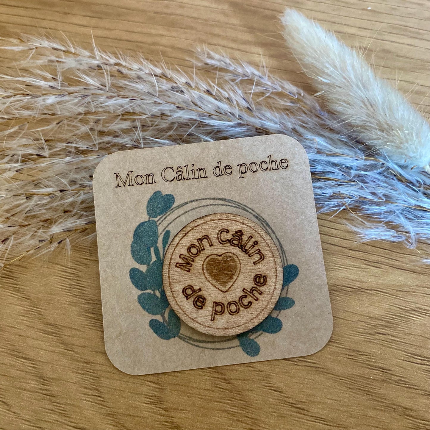 Gros plan sur la précision de la gravure laser sur le bois naturel du câlin de poche "TMon câlin de poche"