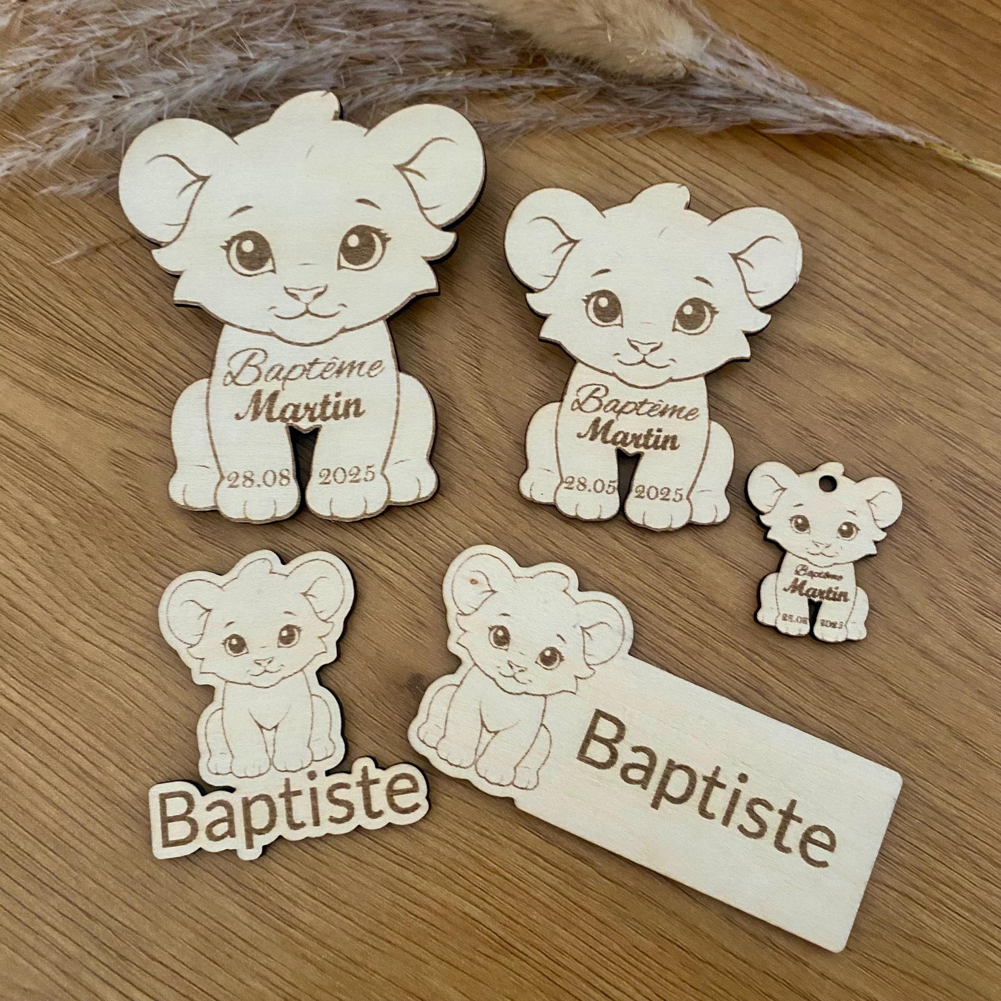 Mise en scène de la collection complète (magnets, marque-places lion, étiquettes) sur une table festive aux tons naturels.