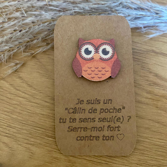 Petite chouette en bois gravée, posée au creux d'une main pour illustrer son format de poche réconfortant.