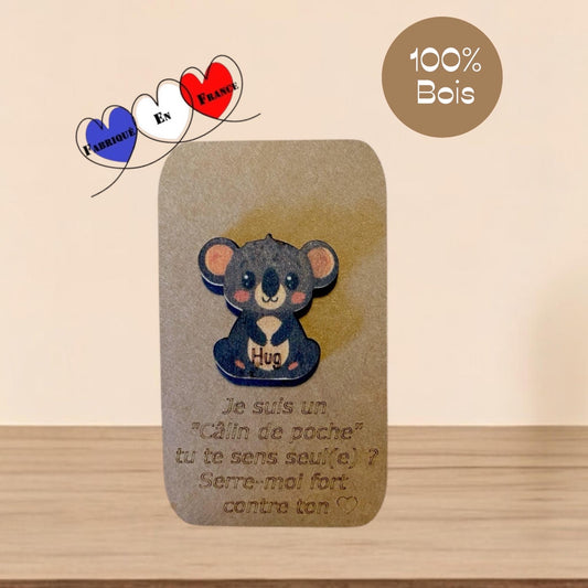 Petit koala en bois gravé, posé délicatement sur une main pour montrer sa taille miniature.