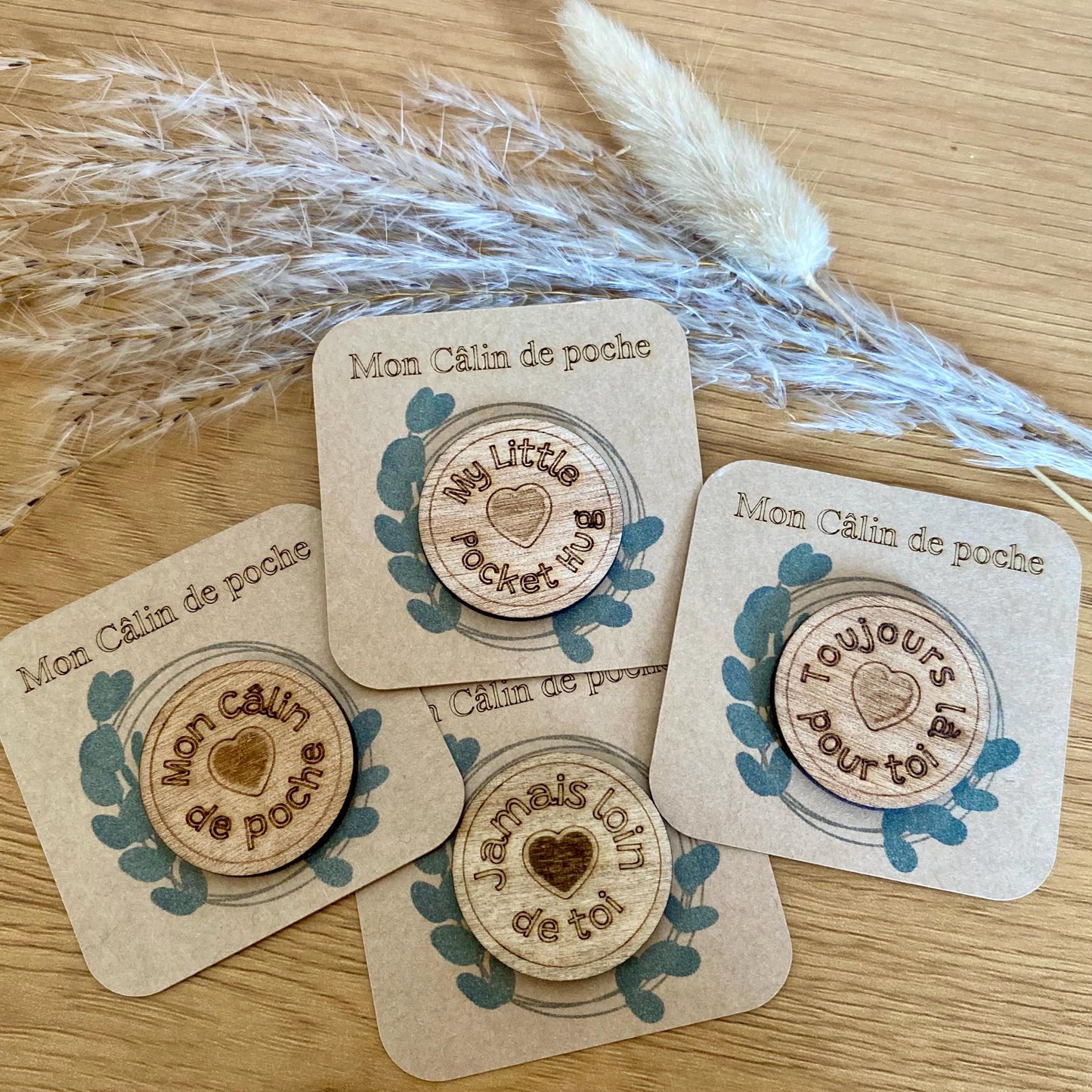 Plusieurs Câlins de Poche en bois avec leurs messages gravés, disposés de manière esthétique.