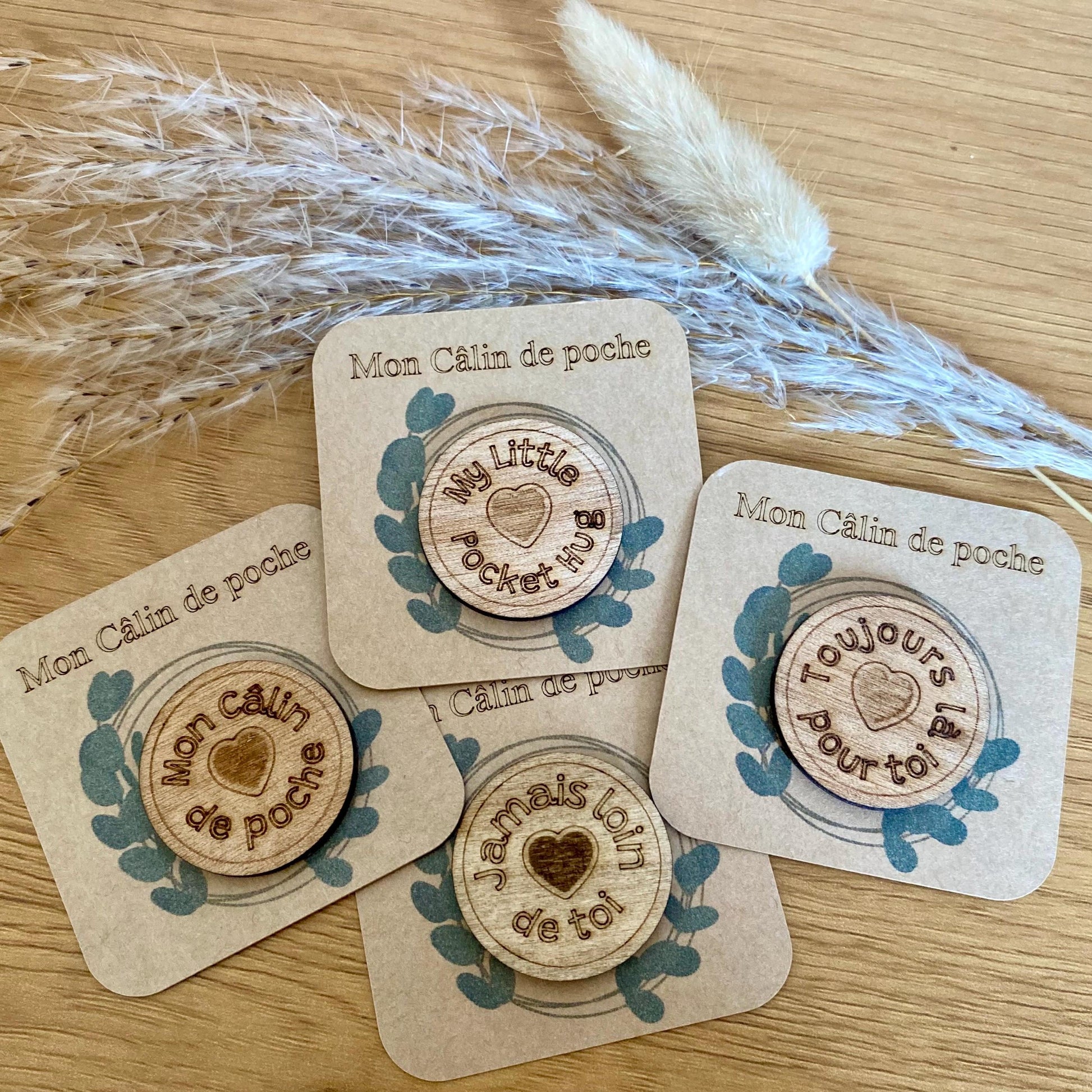 Plusieurs Câlins de Poche en bois avec leurs messages gravés, disposés de manière esthétique.