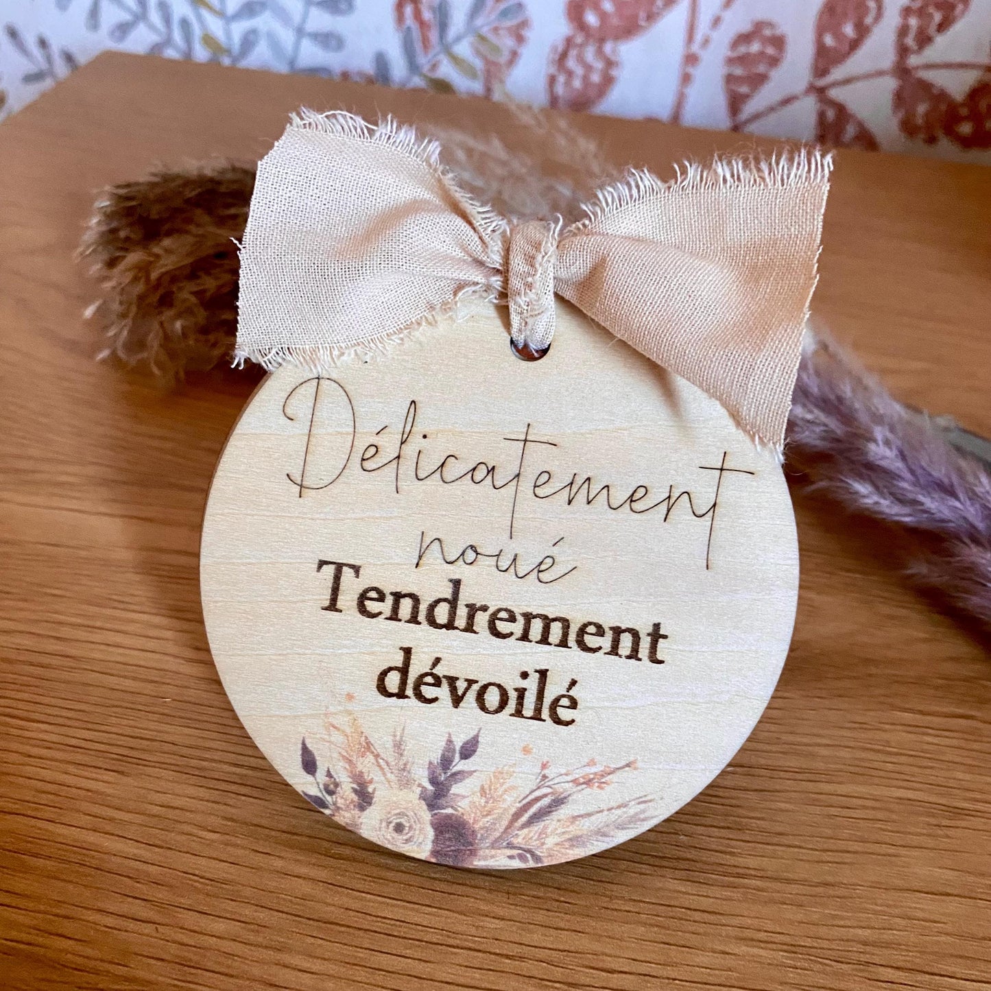 Coffret annonce grossesse composé de deux cartes en bois gravées, maintenues par un ruban lin chic, posé sur un support naturel.