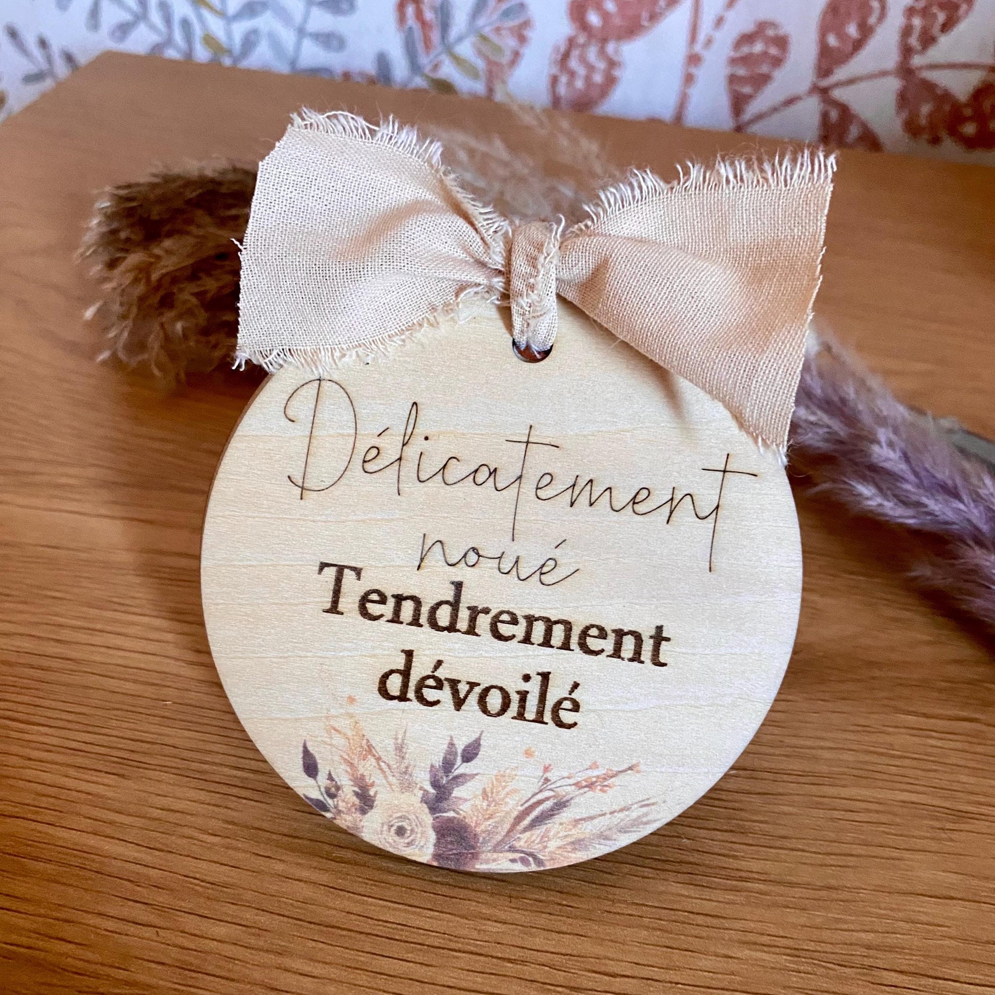 Coffret annonce grossesse composé de deux cartes en bois gravées, maintenues par un ruban lin chic, posé sur un support naturel.