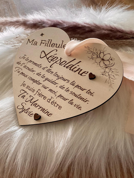 Carte cœur en bois avec ses détails floraux et les deux cœurs en relief, suspendue avec son ruban en mousseline beige.
