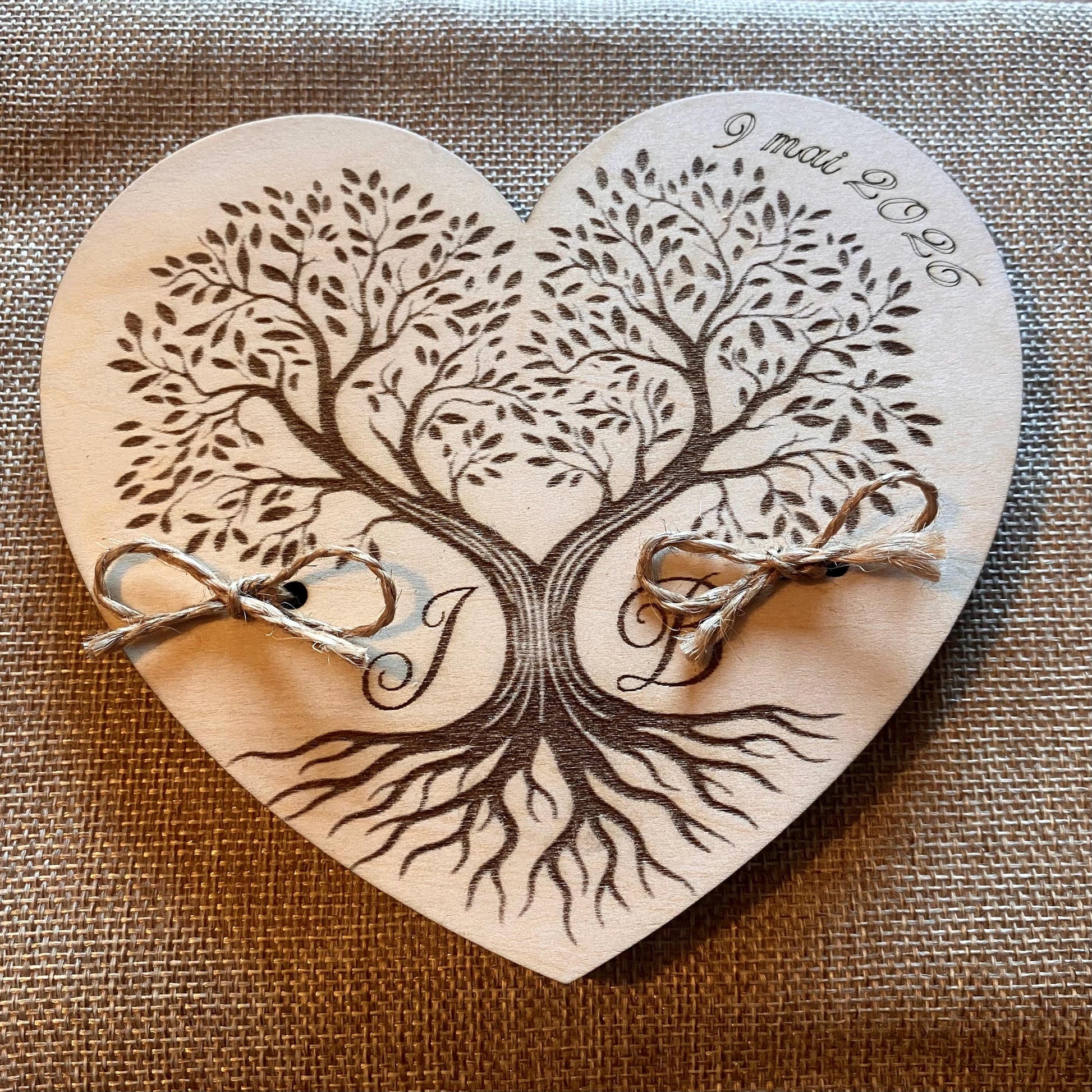 Porte-alliance posé sur une table de mariage décorée, entouré de fleurs et de contenants à dragées assortis.