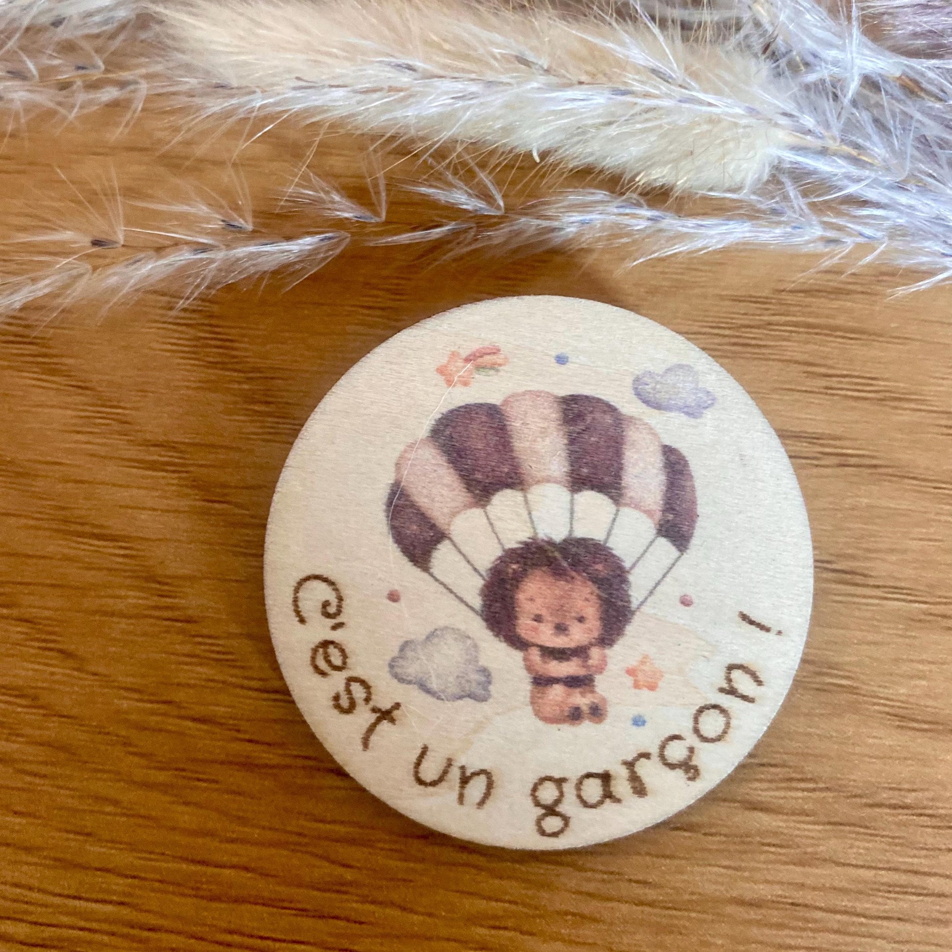 Magnet révélation de sexe affiché sur un réfrigérateur avec une décoration de grossesse autour.