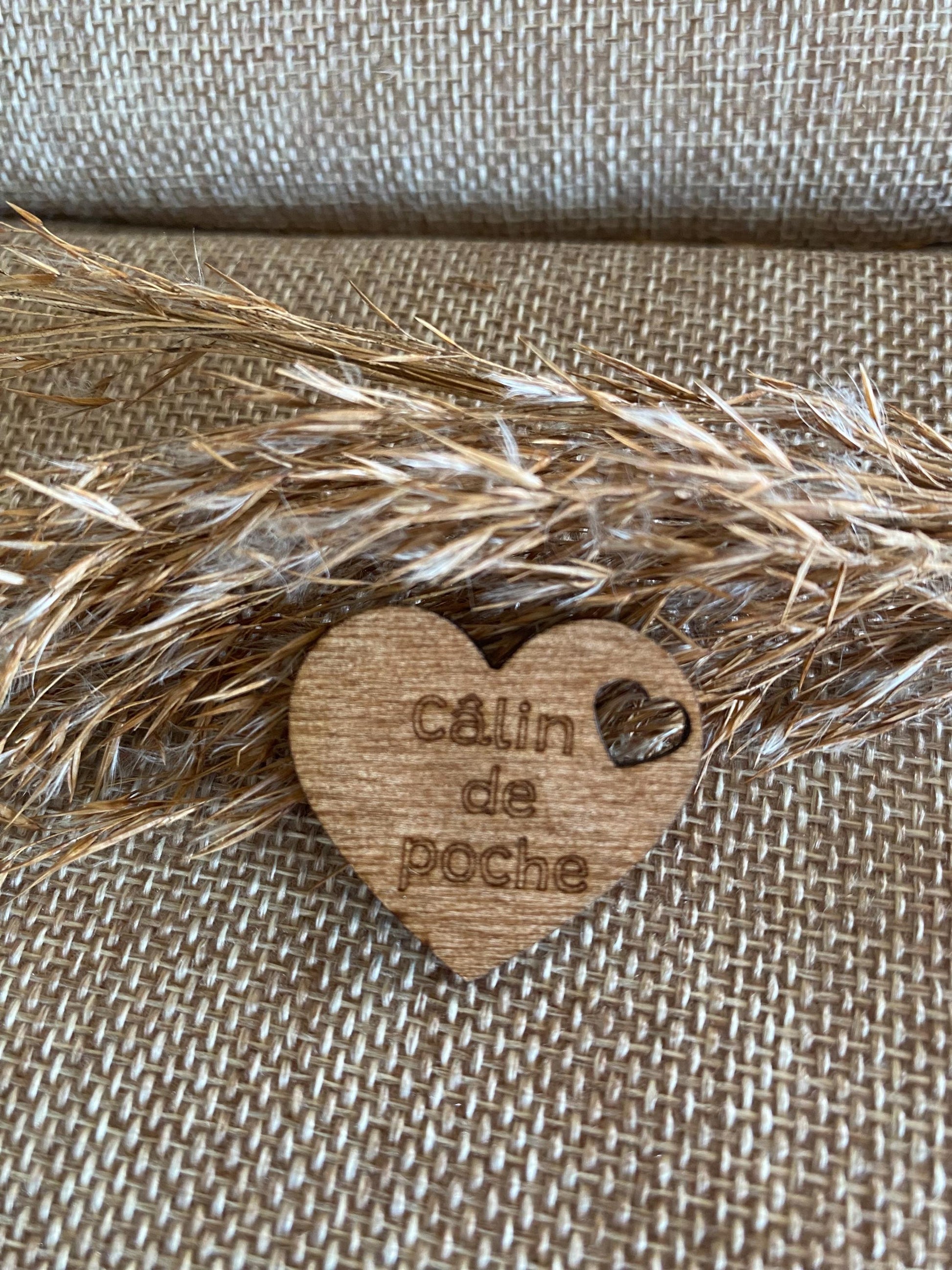Gros plan du câlin de poche coeur  et sur la gravure et le veinage unique du bois.