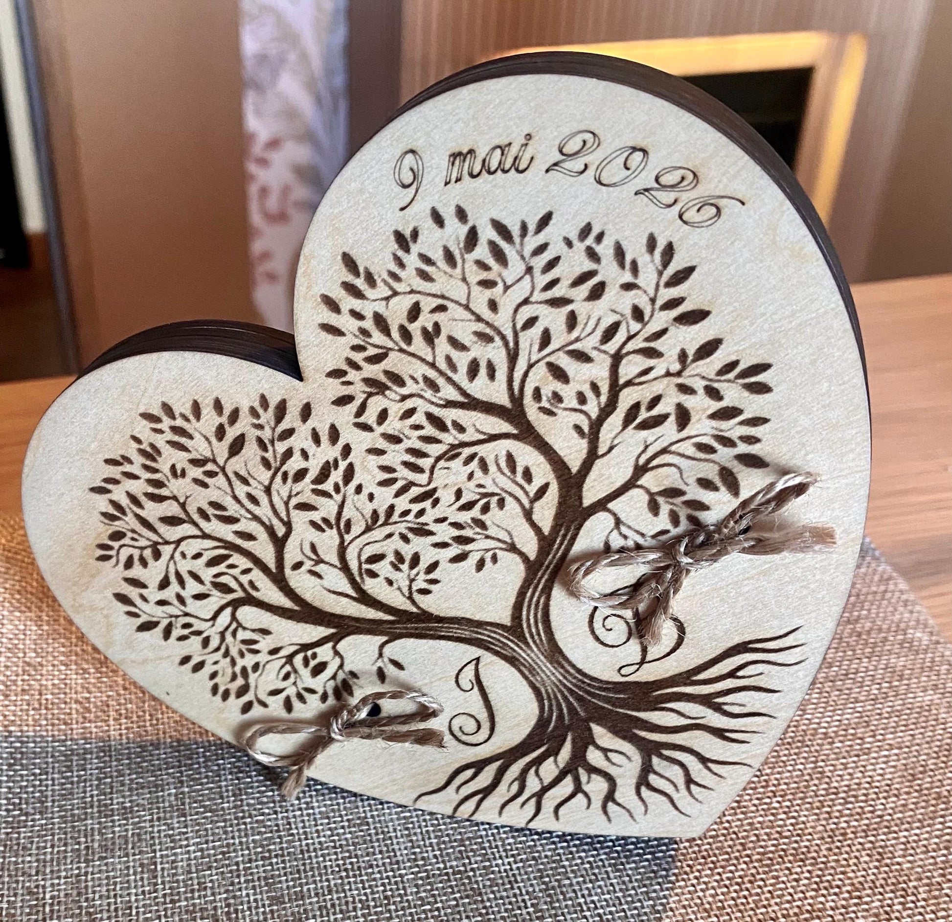 Porte-alliance en bois gravé « Arbre de Vie » avec les alliances déposées dessus.