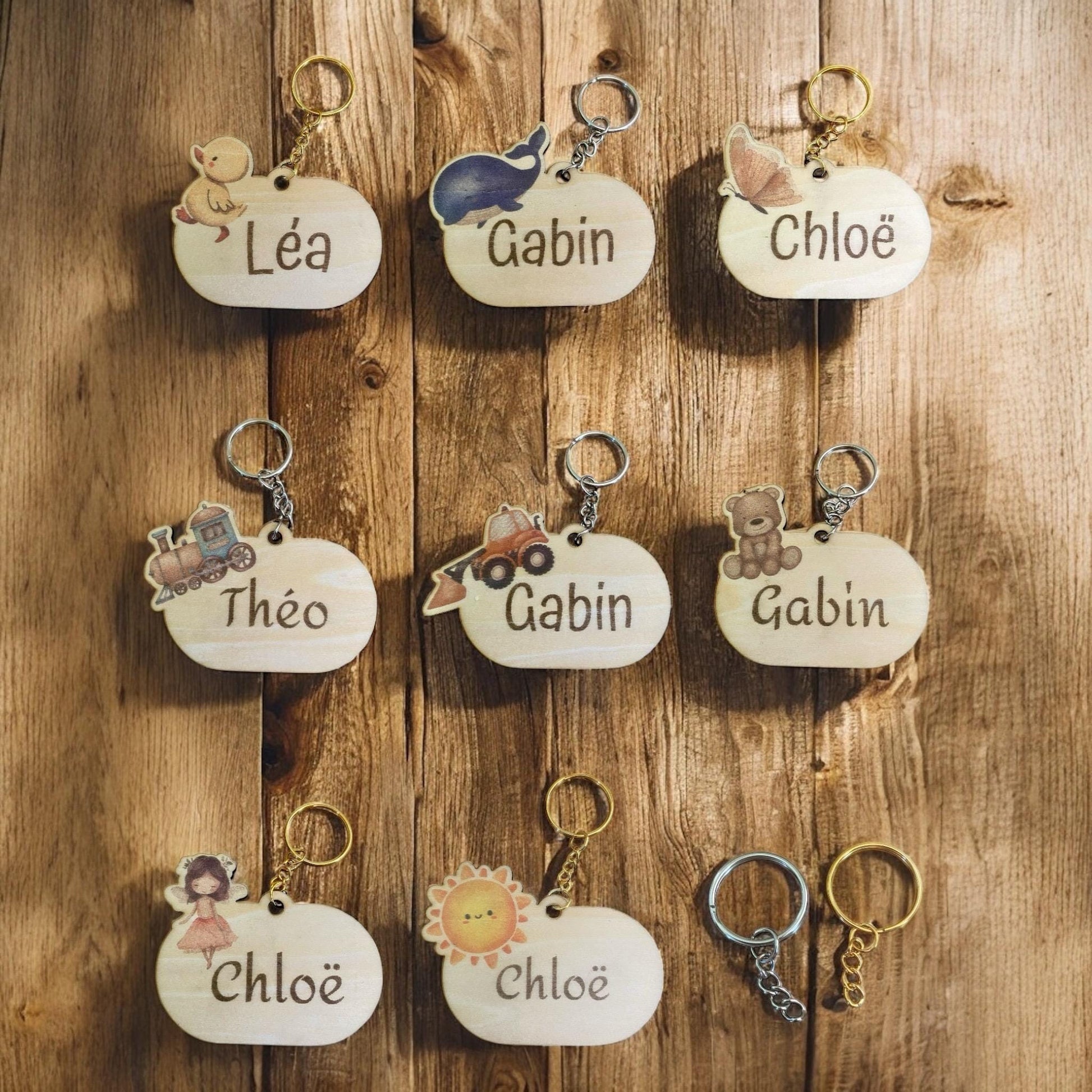 Collection de porte-clés en bois (motifs fée, voiture, ourson) présentés ensemble.