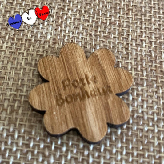 Gros plan sur un trèfle à 4 feuilles en bois posé sur une surface naturelle.